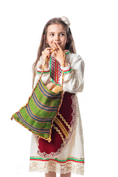 Femme bulgare ou jeune fille en robe folklorique traditionnelle tient dans les mains du blé doré et du pain maison fraîchement cuit dans un sac - Photo, image