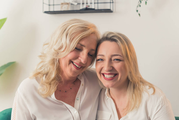 Two blonde women looking alike, wearing snow-white elegant shirts, looking directly at a camera. Females looking at each other with love and cheering. High quality photo - Foto, immagini