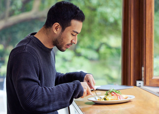 a man enjoying a plate of food in a cafe. - Zdjęcie, obraz