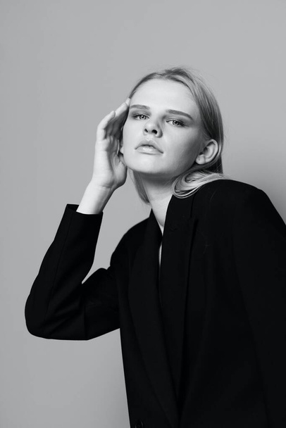 Fashion model meisje poseren met haar handen omhoog in de studio in zwart-wit stijl in een klassiek jasje. Hoge kwaliteit foto - Foto, afbeelding
