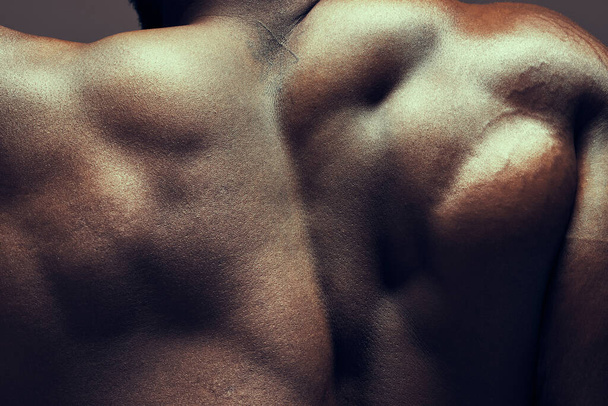 a muscular man posing against a studio background. - Фото, зображення