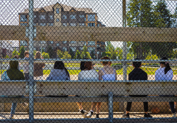 Летние занятия для школьников. Дети играют в футбол, футбол на открытом стадионе. Группа студентов наблюдает за спортивным мероприятием на стадионе. Уличное фото, выборочный фокус-июнь 2022 года - Ванкувер Канада - Фото, изображение