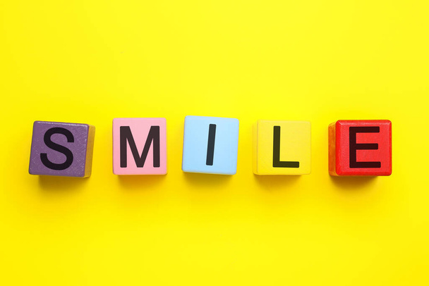 Cubos brillantes con palabra SMILE sobre fondo amarillo - Foto, Imagen
