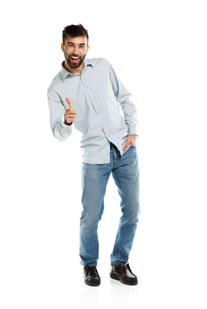 Een jonge bebaarde man die lacht met een vinger geïsoleerd op wit - Foto, afbeelding