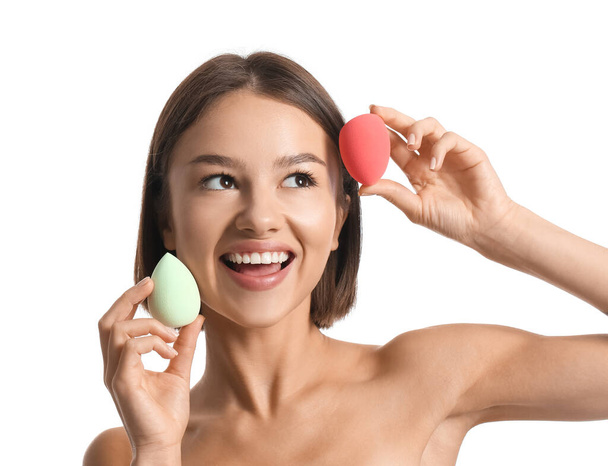 Pretty young woman with makeup sponges on white background - Foto, imagen