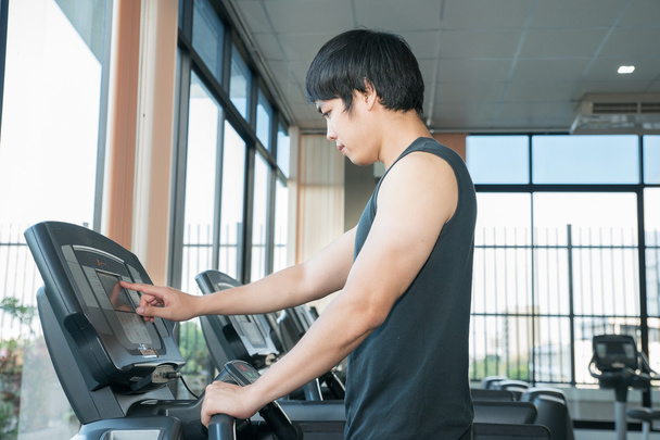 Az ember az edzőteremben csinál fitness futópad beállítása - Fotó, kép