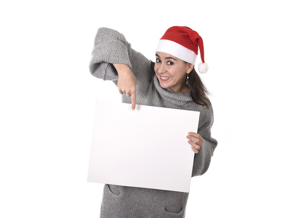 young sweet Latin woman in Santa Christmas hat pointing blank billboard  - Photo, Image