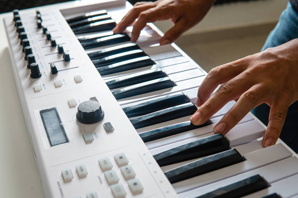 Close up of hands and keyboard playing a song in a music studio. Two hands on the keys of the keyboard. Playing a song on the piano. Professional musician playing keyboard. - Photo, image