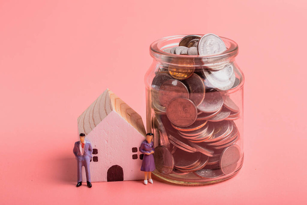 Miniature people, business men and women with house coins. Savings ideas for future home buying. - Zdjęcie, obraz