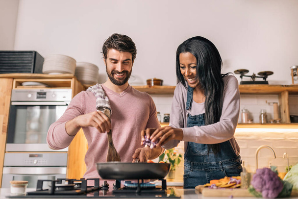 Cute couple smiling and preparing lunch together in the kitchen at home. - Fotoğraf, Görsel