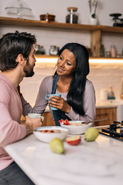 Smiley black woman and her boyfriend having delicious breakfast in the kitchen at home. - Foto, Imagen