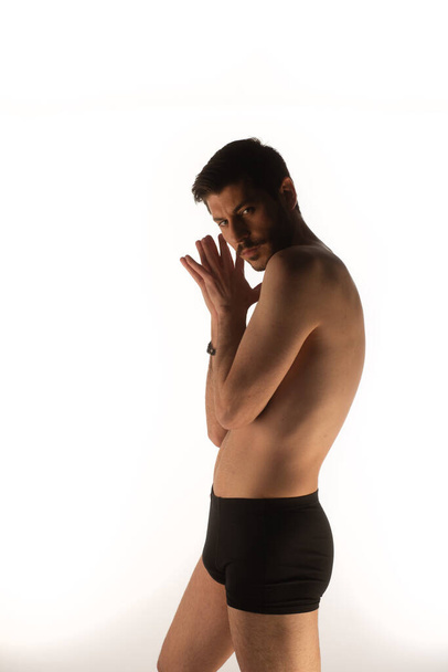 Attraktiver und sexy Mann im Studio macht verführerische Posen und berührt sich selbst - Foto, Bild