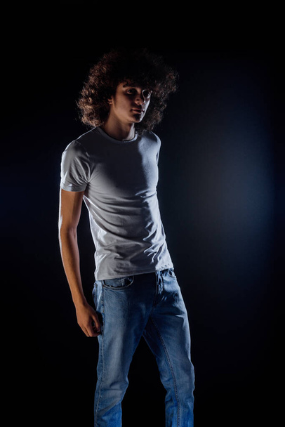 Jeune homme élégant hipster en vêtements à la mode posant dans un studio moderne - Photo, image