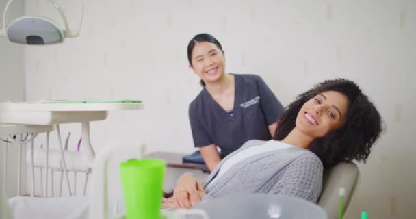 Ортодонт і пацієнт посміхаються ідеальними зубами в консультації. Жінка відчуває впевненість у призначенні послуги відбілювання порожнини рота в клініці охорони здоров'я або приватній практиці
. - Кадри, відео