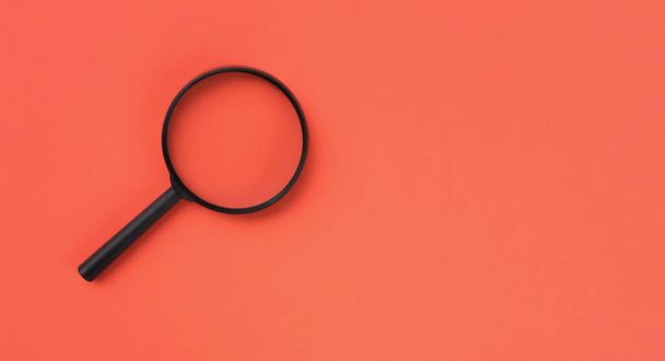 loupe or magnifying glass as internet search symbol. orange background with copy space - Photo, Image