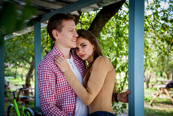 The guy with a girl hugs near a wooden house in the garden - Fotoğraf, Görsel