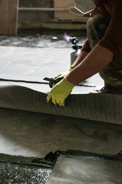 The worker untwists the roll of waterproofing and fastens it to the resin, installing waterproofing. - Photo, Image