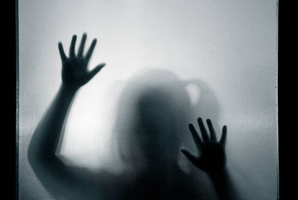 Horror ghost girl behind the matte glass in black and white. Halloween festival concept. - 写真・画像