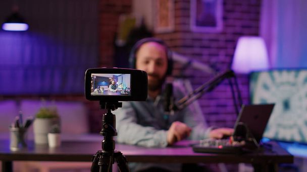 Selective focus on digital video camera screen recording influencer caucasian man streaming live talk show using microphone from home studio. Male content creator filming vlog for social media post. - Photo, Image