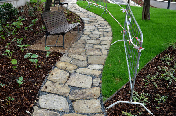 gray stone in a garden with a stone nature path to the arches near the lawns covered with snow. garden walkway made of slate boards side by side in lawn park architecture. ornamental stone, slate - Foto, Imagem