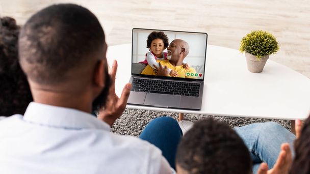 Famille noire utilisant un ordinateur portable pour un appel vidéo à la maison, parlant à un homme afro-américain âgé avec enfant, Groupe de personnes agitant les mains à la caméra Web, Profitant de la communication en ligne, Collage - Photo, image