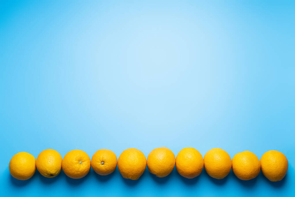 Плоская с рядами из апельсинов на синем фоне - Фото, изображение