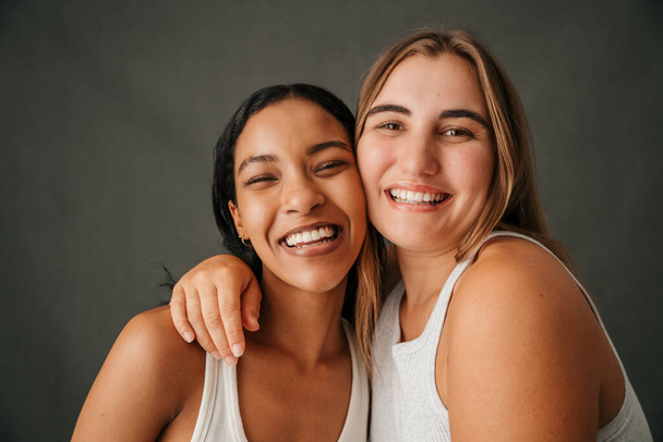 Close up of two happy smiling girlfriends in a studio posing . High quality photo - 写真・画像