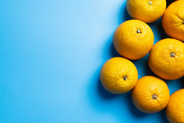 Top view of natural oranges on blue surface - 写真・画像