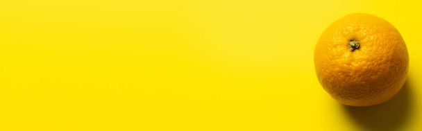 Top view of orange with shadow on yellow background, banner  - Foto, Bild