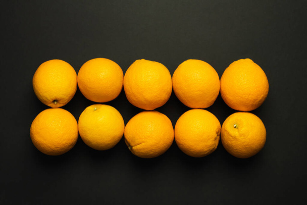 Top view of fresh oranges in rows isolated on black  - 写真・画像