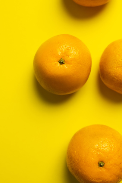 Top view of bright tangerines on yellow background - 写真・画像