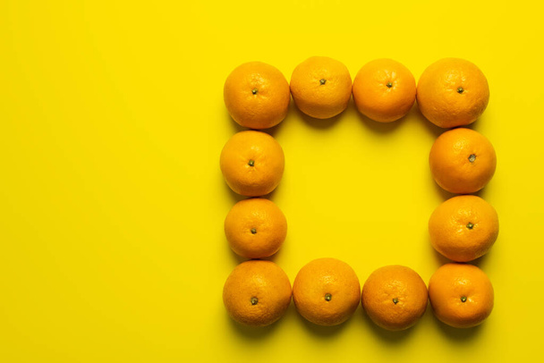 Colocación plana con marco de mandarinas sobre fondo amarillo - Foto, imagen