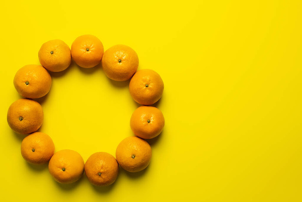 Vista superior del marco de mandarinas dulces con sombra sobre fondo amarillo - Foto, Imagen