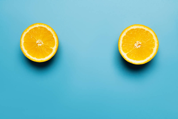 Top view of bright and cut orange on blue background - Foto, afbeelding