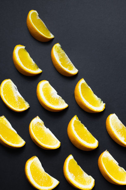 Flat lay with pieces of oranges on black background - Φωτογραφία, εικόνα