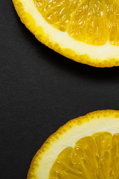 Close up view of natural orange slices on black background - Foto, afbeelding