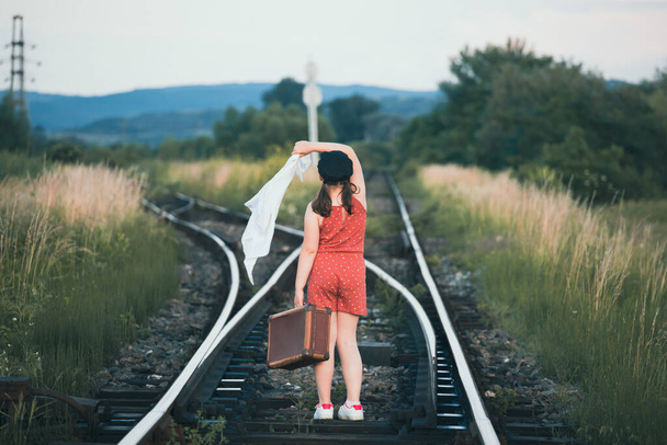 Retro styled photo of little girl with old luggage at the railways - Zdjęcie, obraz