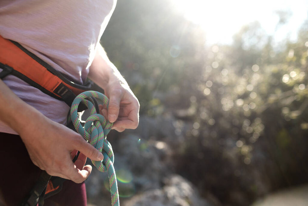 Ein Bergsteiger bereitet Ausrüstung für das Klettern vor, eine Frau hält ein Seil in der Hand, ein Bergsteiger bindet einen Knoten - Foto, Bild