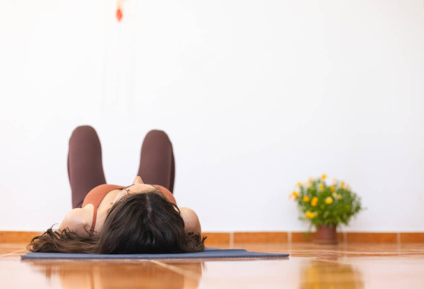la ragazza si trova sul tappeto e si riposa dopo aver fatto yoga. allenamento a casa. - Foto, immagini