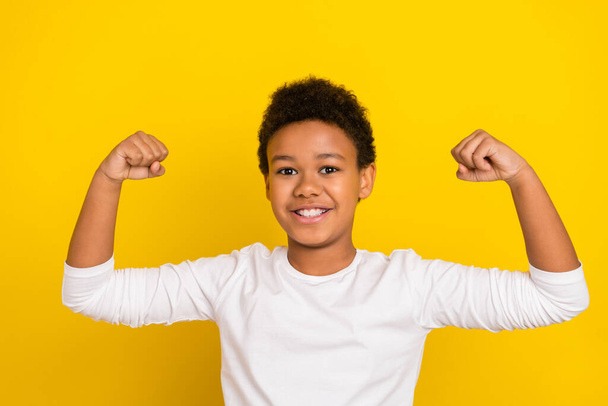 Portrait of positive confident pupil arms demonstrate flexing biceps isolated on yellow color background. - Foto, Imagen