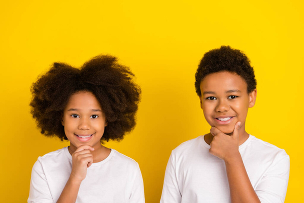 Photo of two beautiful minded thoughtful siblings hand chin look camera isolated on yellow color background. - Foto, Bild