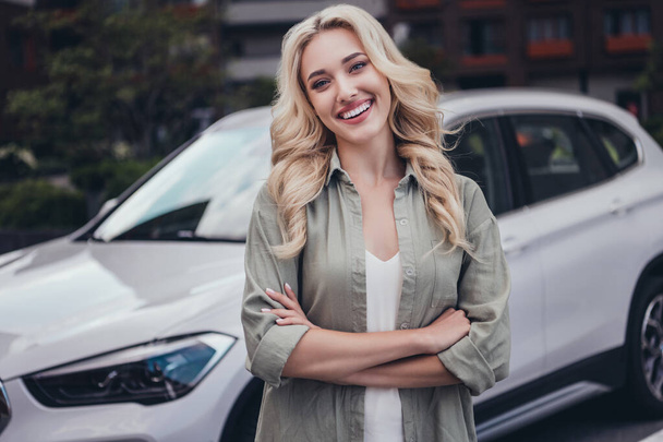 Portrait of attractive cheerful wavy haired girl taking modern car for rent spending day holiday weekend outside. - Photo, image