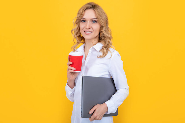 smiling blonde woman with coffee cup and laptop on yellow background. - Fotografie, Obrázek