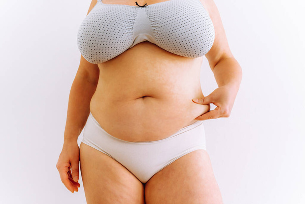 woman demonstrates saggy fat on thighs, fat belly is result of age-related changes, unhealthy eating, lack of diet - Foto, imagen