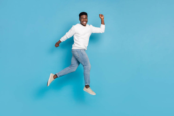 Full length photo of cheerful overjoyed man run jump have good mood isolated on blue color background. - Foto, imagen