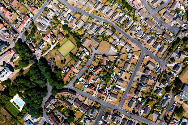 Una vista aérea directamente por encima de una comunidad suburbana en las afueras de una ciudad con caminos entrelazados y barrios - Foto, imagen