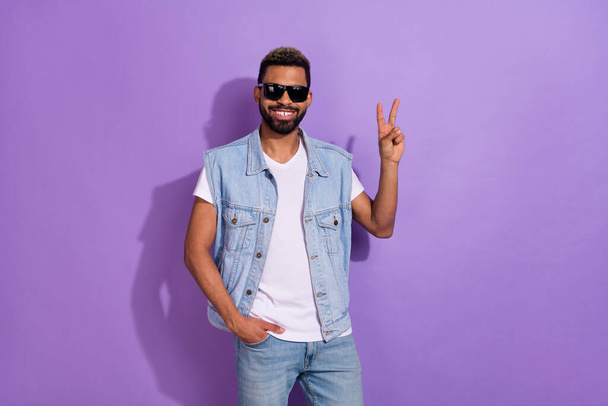 Photo of cute charming man wear jeans waistcoat dark glasses showing v-sign isolated violet color background. - Φωτογραφία, εικόνα