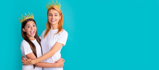 Mother and daughter child banner, copy space, isolated background. Happy woman and girl child in crowns hug smiling blue background, mother - Photo, Image