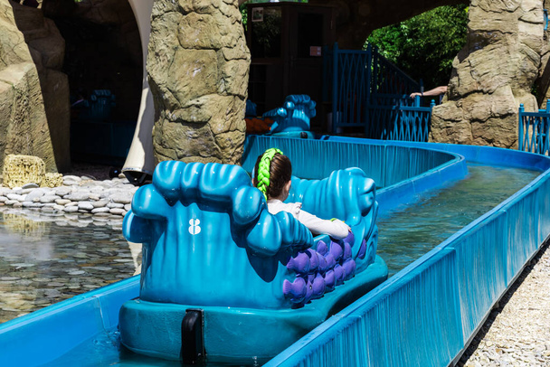Una ragazza galleggia sull'acqua in un labirinto blu in un parco divertimenti. Estate acqua attrazione per bambini. - Foto, immagini