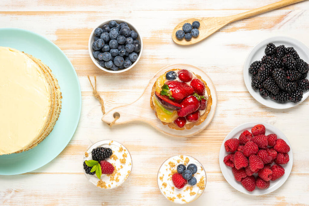 Sweet desserts with fresh berries on wooden background. - Zdjęcie, obraz